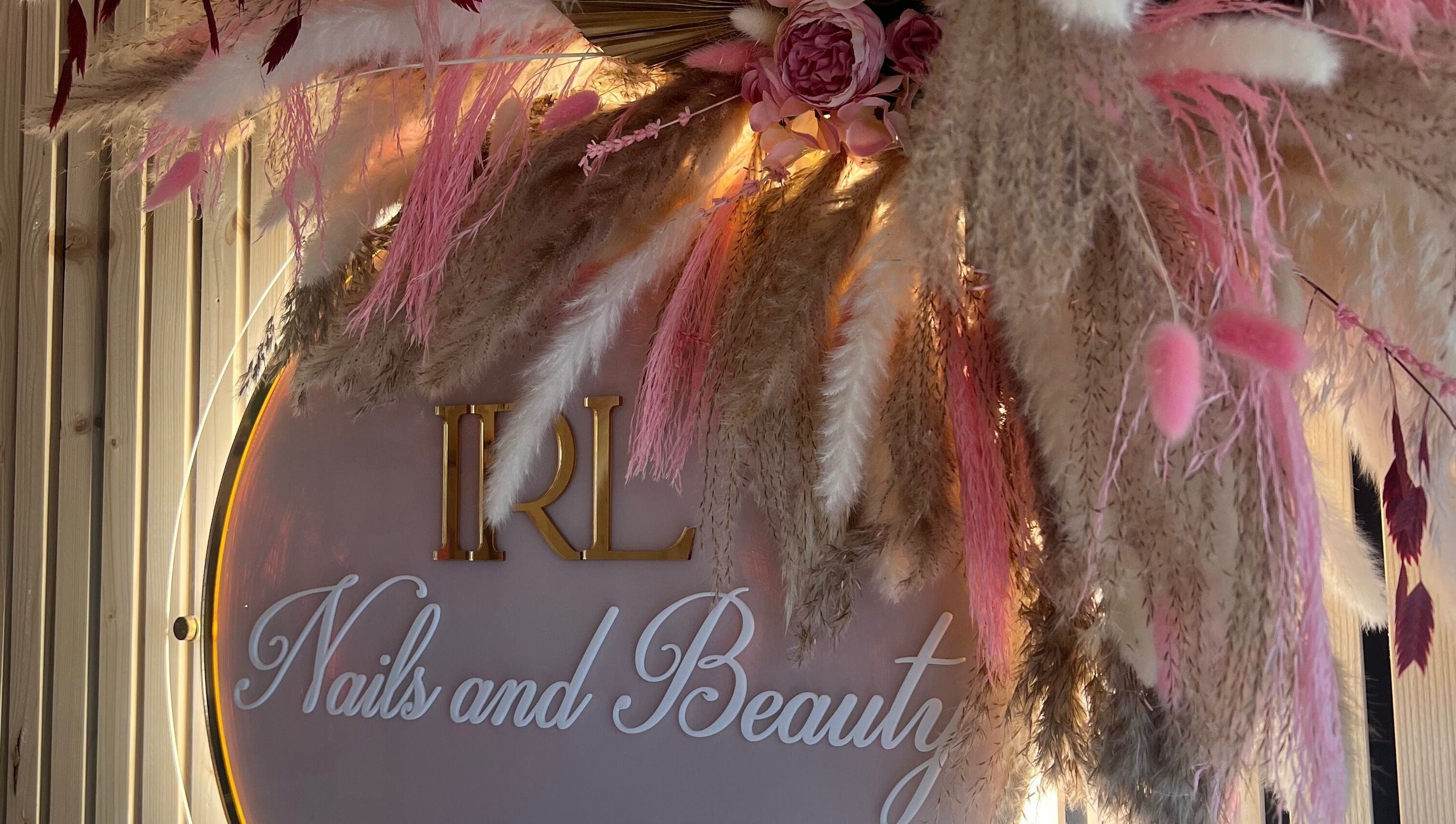 Floral decor at IRL Nails and Beauty, Leicester, England, GB. Elegant branding signage surrounded by pink florals.
