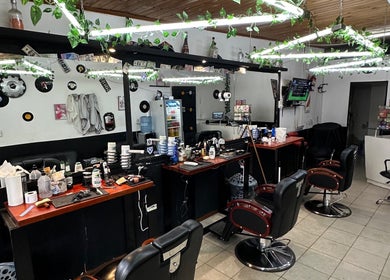 Interior de Astu Barber, Pérez, Santa Fe, AR, con sillas y espejos decorados con plantas.