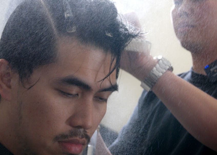 Stylist spraying client's hair at Whistle & Flute Barber Studio, Auckland, Auckland, NZ.