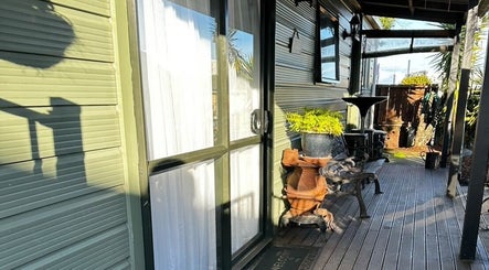Charming veranda at Pam Thai Hand Massage, Taupō, Waikato Region, NZ, with potted plants and a wooden bench.