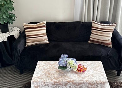 Comfortable lounge at Pam Thai Hand Massage, Taupō, Waikato Region, NZ with black sofa and floral decor.