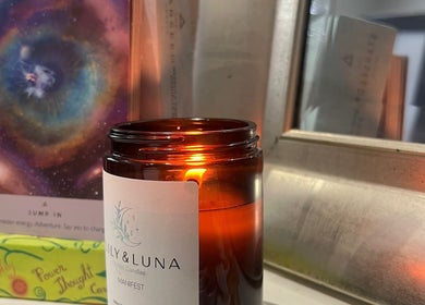 A lit amber candle next to cosmic artwork at Earth Glow Holistic Wellness, Preston, England, GB.