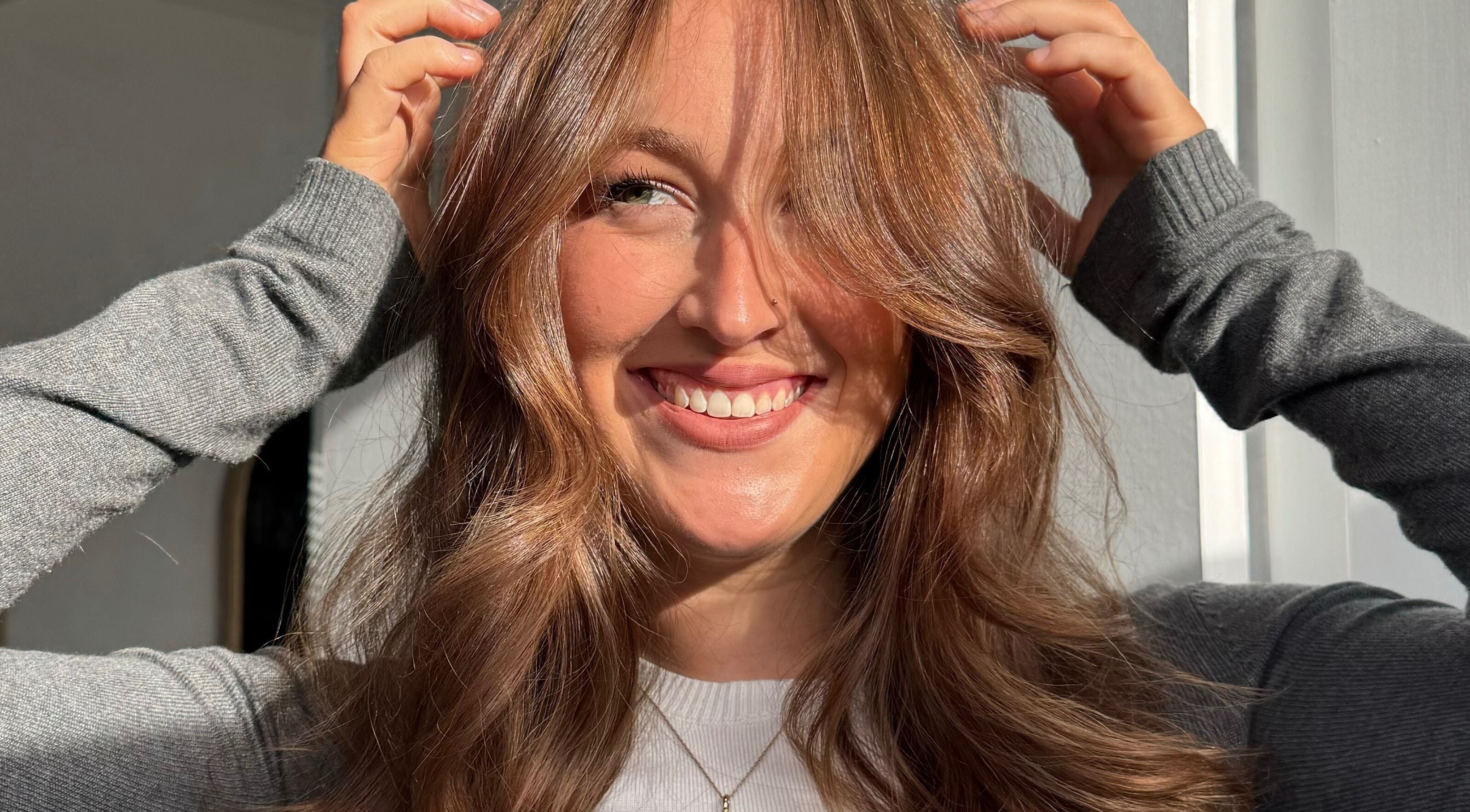 Smiling woman with styled hair at IM HAIR, Engadine, New South Wales, AU, bathed in natural light.