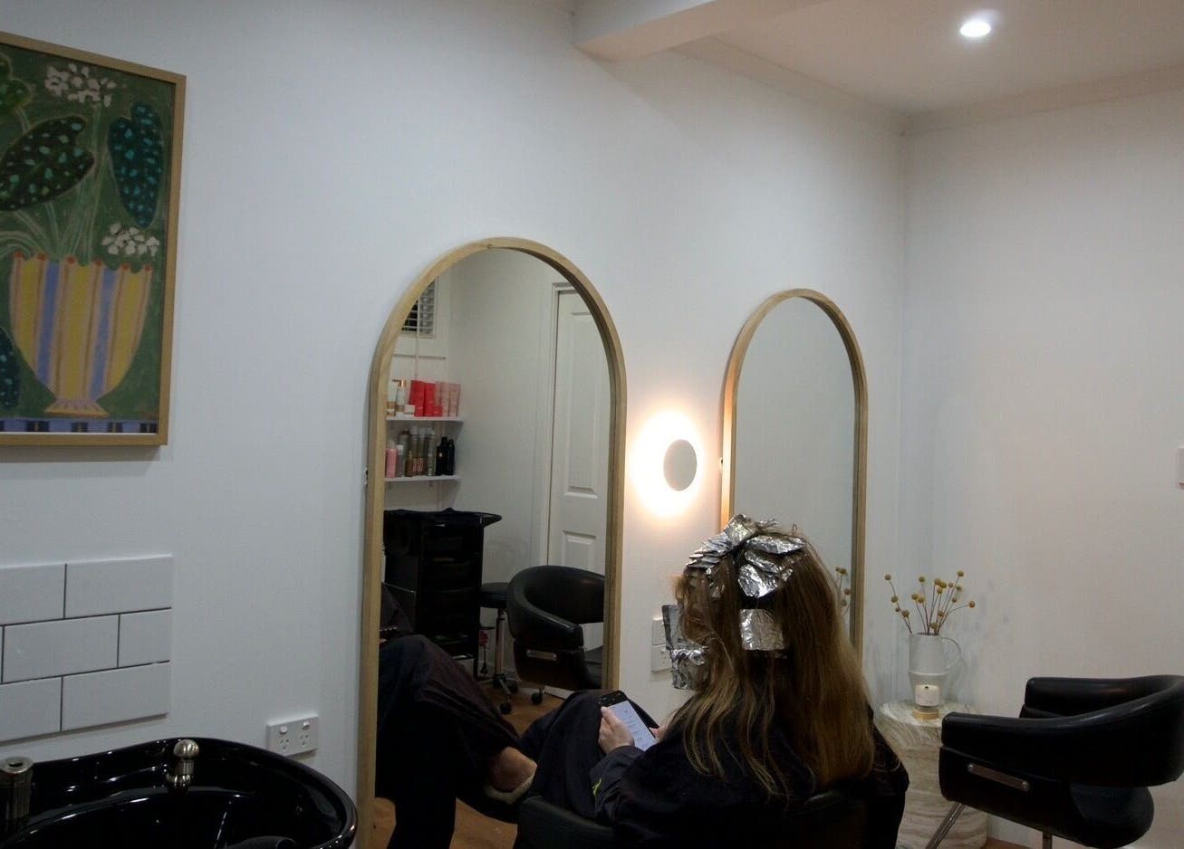 Client at IM HAIR, Engadine, NSW, AU, enjoying hair treatment in a stylish salon setting.