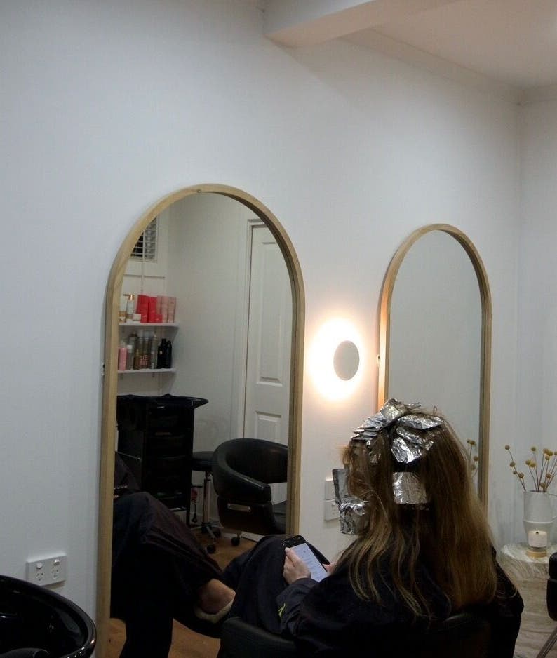 Client at IM HAIR, Engadine, NSW, AU, enjoying hair treatment in a stylish salon setting.
