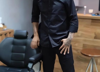 Barbeiro na Favela Barbershop em Frankfurt Am Main, Hessen, DE, ao lado de cadeira profissional.
