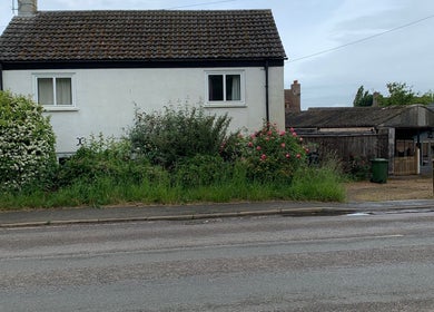 Exterior view of Happy Hounds Dog Grooming, Wisbech Saint Mary, England, featuring rustic charm and lush greenery.
