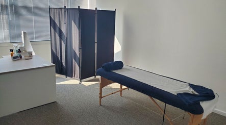 Massage room at The Reboot Room, Camberley, England, GB with a treatment bed and privacy screen.