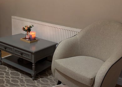 A serene relaxation corner at Sirinthra Beauty & Massage, Blackburn, England, GB featuring a cozy chair and candlelit table.