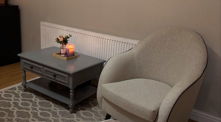 A serene relaxation corner at Sirinthra Beauty & Massage, Blackburn, England, GB featuring a cozy chair and candlelit table.