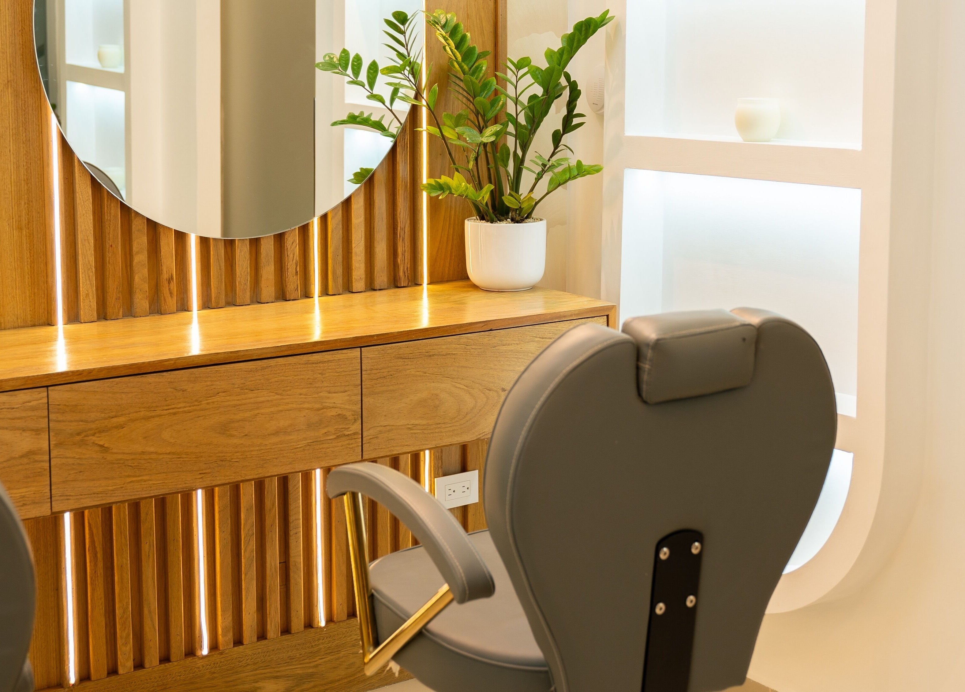 Elegante silla de salón en Cactus Beauty, Santiago De Los Caballeros, Santiago, DO con un espejo redondo y planta decorativa.