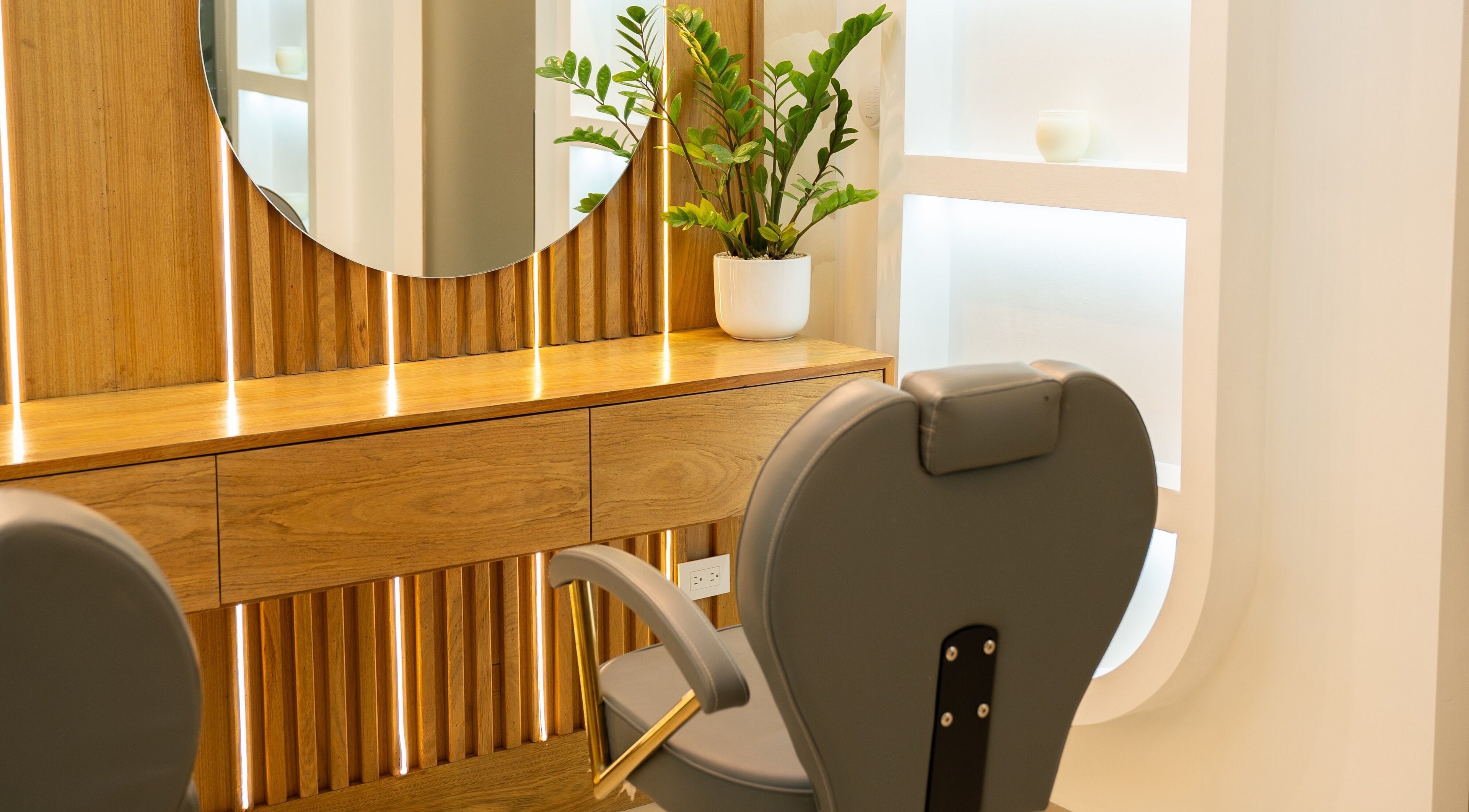 Elegante silla de salón en Cactus Beauty, Santiago De Los Caballeros, Santiago, DO con un espejo redondo y planta decorativa.