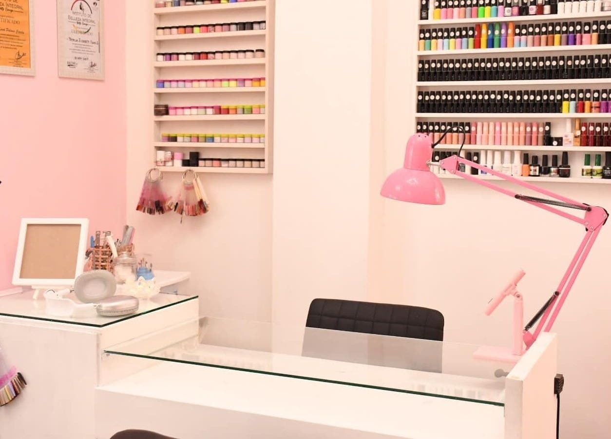 Mesa de manicura en KC Beauty Salon, Saltillo, Coahuila De Zaragoza, MX, con lámpara rosa y esmaltes organizados.