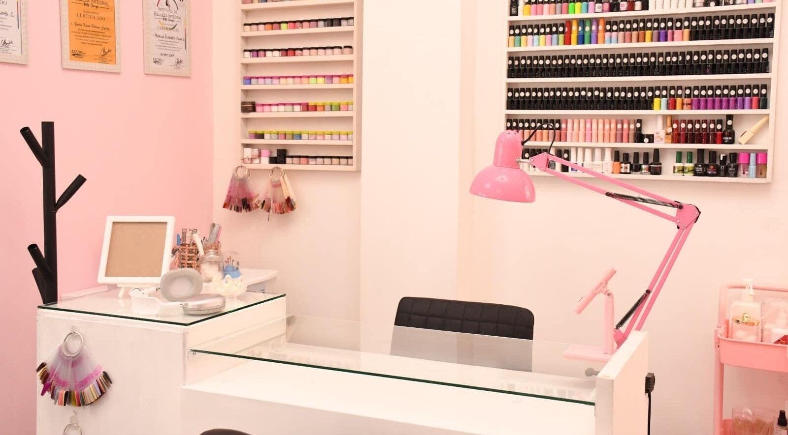 Mesa de manicura en KC Beauty Salon, Saltillo, Coahuila De Zaragoza, MX, con lámpara rosa y esmaltes organizados.