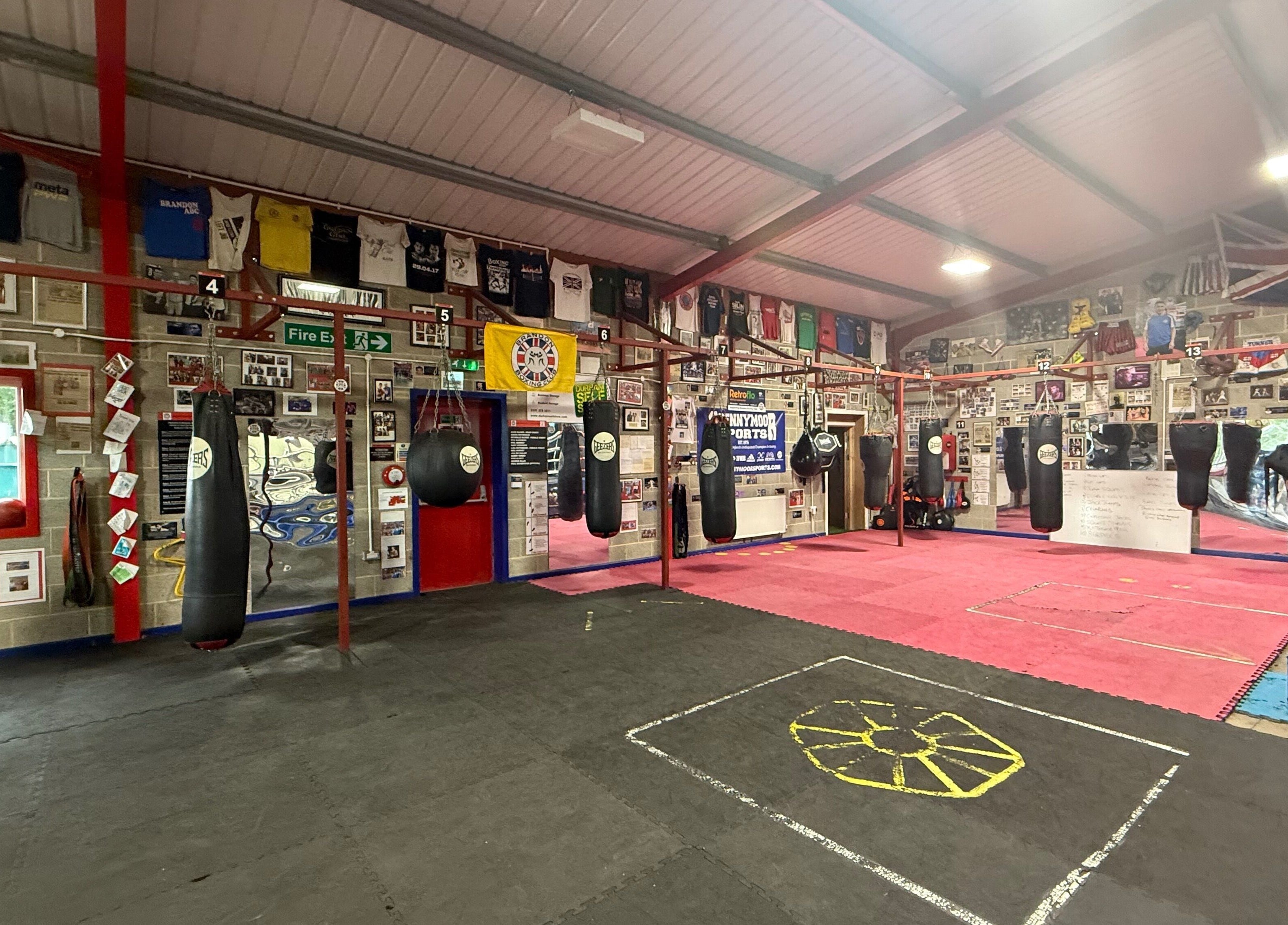 Train With TNT gym in Brandon, England, GB features a dynamic boxing area with hanging bags and vibrant decor.