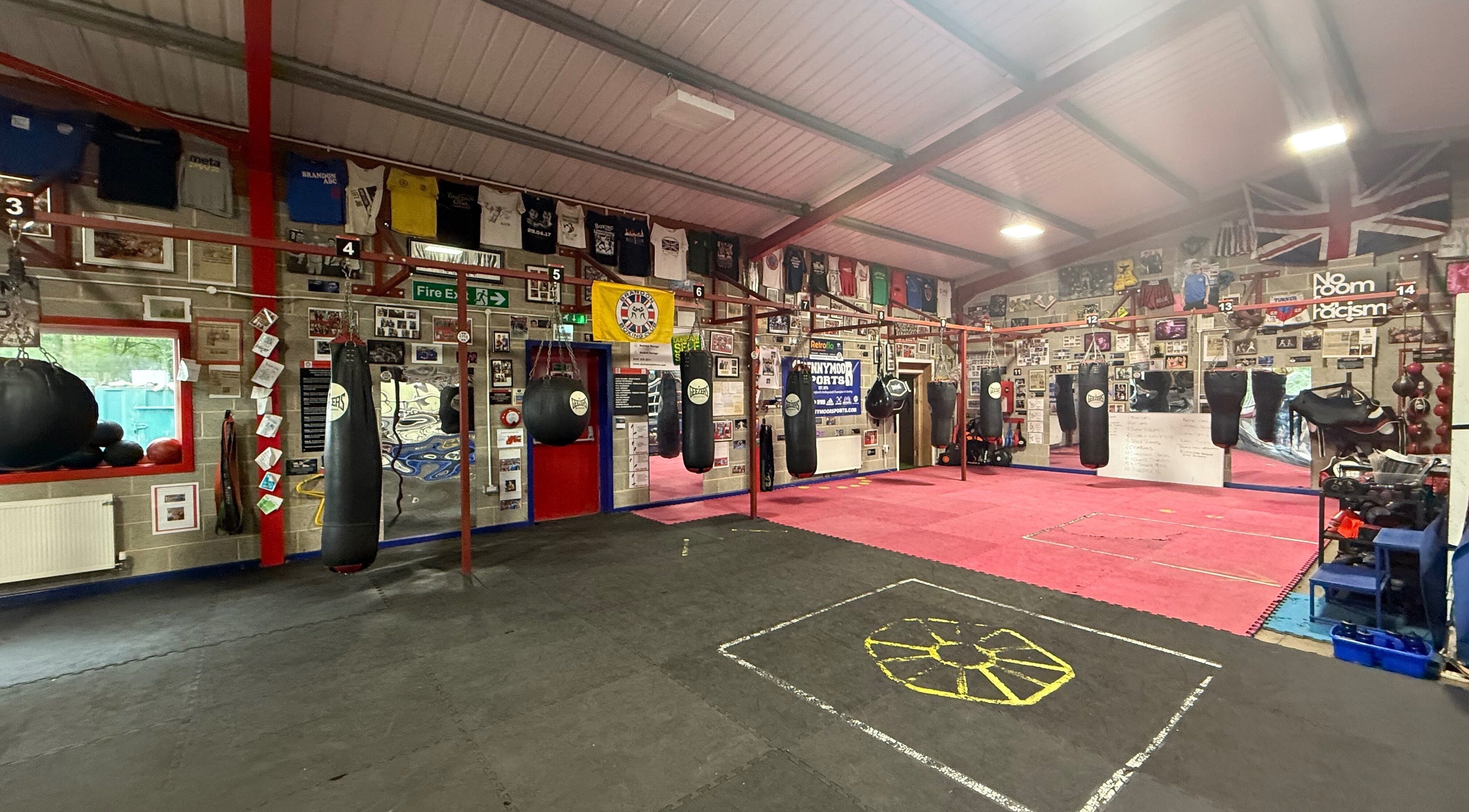 Train With TNT gym in Brandon, England, GB features a dynamic boxing area with hanging bags and vibrant decor.