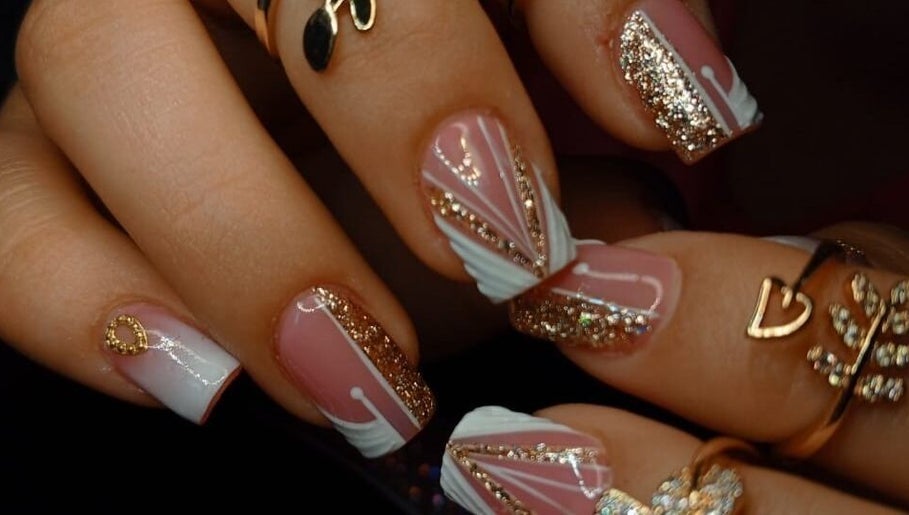 Diseño elegante de uñas en Babys_Nails_Caracas, Caracas, VE, con brillo dorado y detalles artísticos.