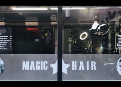 Entrée du salon Magic Hair à Leuze-en-hainaut, Région Wallonne, BE, avec fenêtres et logo distinctif.