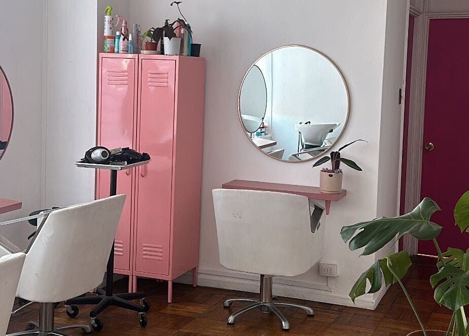 Interior del salón Taller Capilar en Concepción, Bío Bío, CL con decoración rosa y sillas blancas.