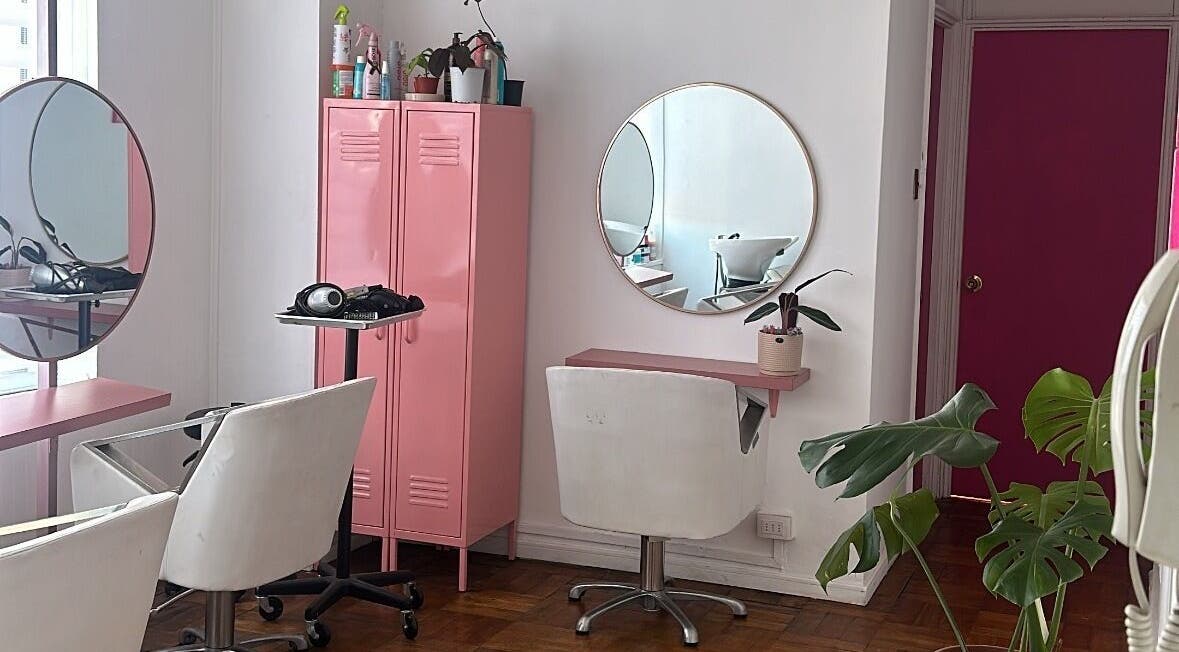 Interior del salón Taller Capilar en Concepción, Bío Bío, CL con decoración rosa y sillas blancas.