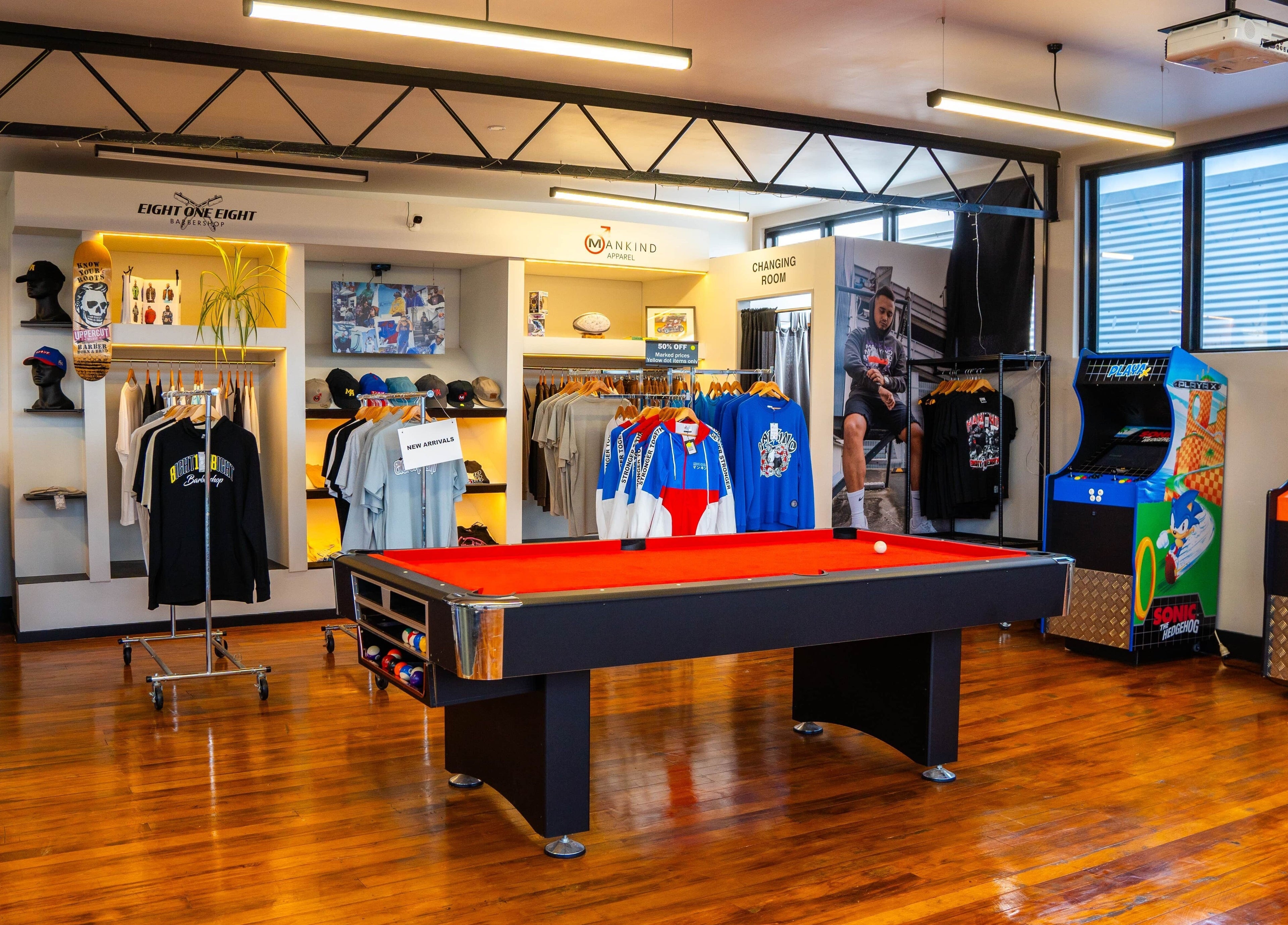 Eight One Eight Barbershop in Auckland, NZ, features shirts, pool table, arcade games, creating a vibrant atmosphere.