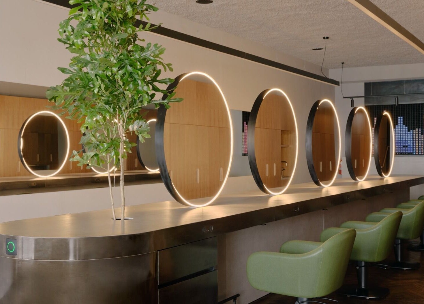 Modern salon interior with stylish round mirrors and green chairs at Zucci South Melbourne, Melbourne, Victoria, AU.