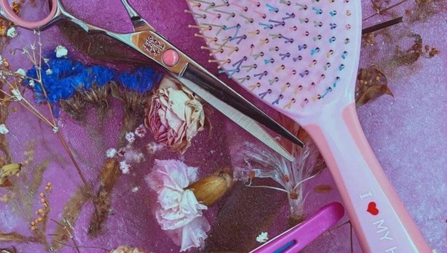 Colorful hairbrush and scissors on floral backdrop at 828_LuxBeauty, Manchester, Missouri, US.