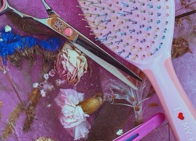 Colorful hairbrush and scissors on floral backdrop at 828_LuxBeauty, Manchester, Missouri, US.