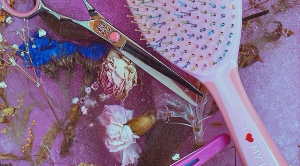 Colorful hairbrush and scissors on floral backdrop at 828_LuxBeauty, Manchester, Missouri, US.