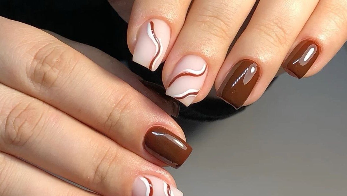 Elegant brown and white swirl nails design at Dolled Beauties & Gents, ZA, showcasing expert styling.