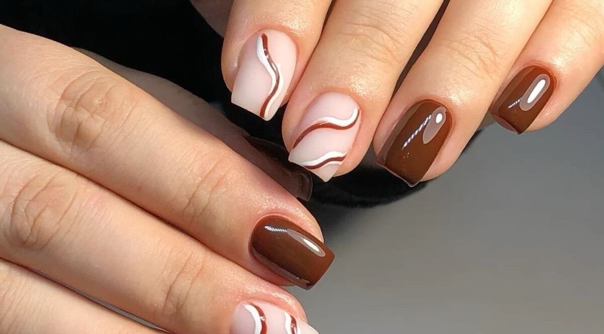 Elegant brown and white swirl nails design at Dolled Beauties & Gents, ZA, showcasing expert styling.