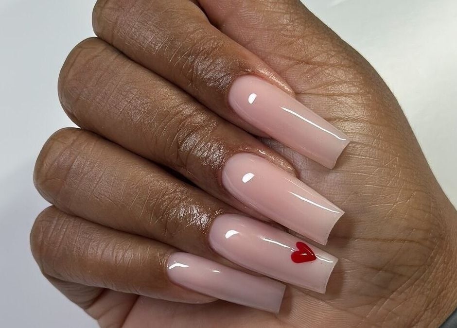 Stylish polished nails with red heart design at Dolled Beauties & Gents in ZA.