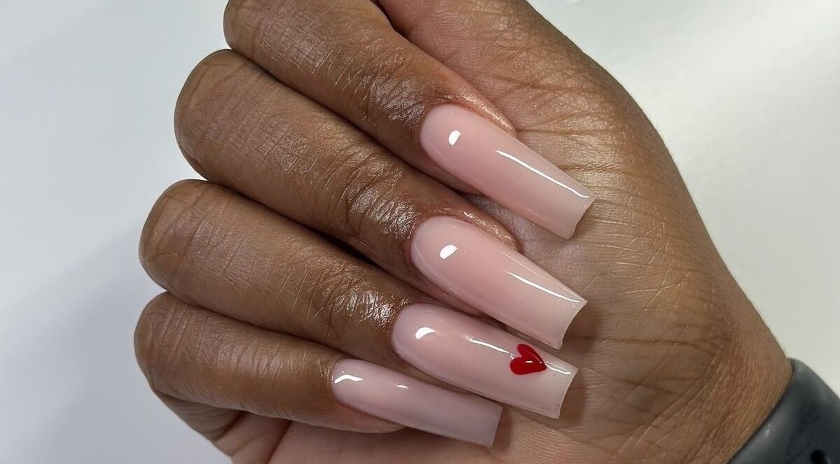 Stylish polished nails with red heart design at Dolled Beauties & Gents in ZA.