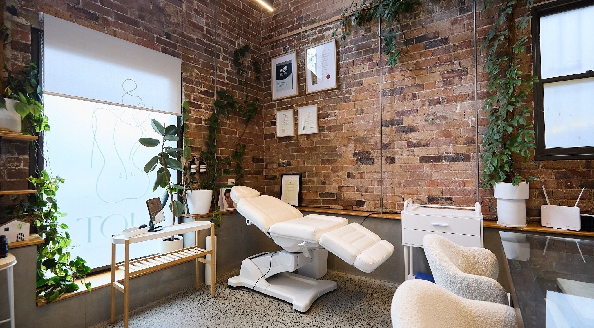 Relaxing treatment room at Nurse Amy Aesthetics, Paddington, New South Wales, AU with lush greenery and certificates.