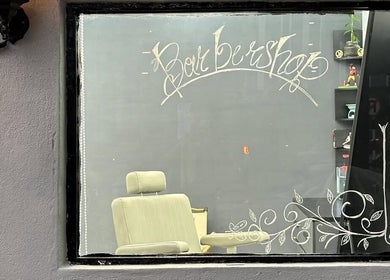 Inside view of Nul’s Barbershop through decorated window in Batu Caves, Selangor, MY featuring a barber chair.