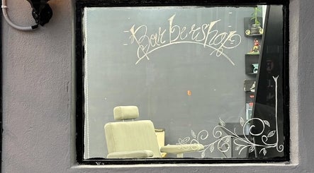 Inside view of Nul’s Barbershop through decorated window in Batu Caves, Selangor, MY featuring a barber chair.