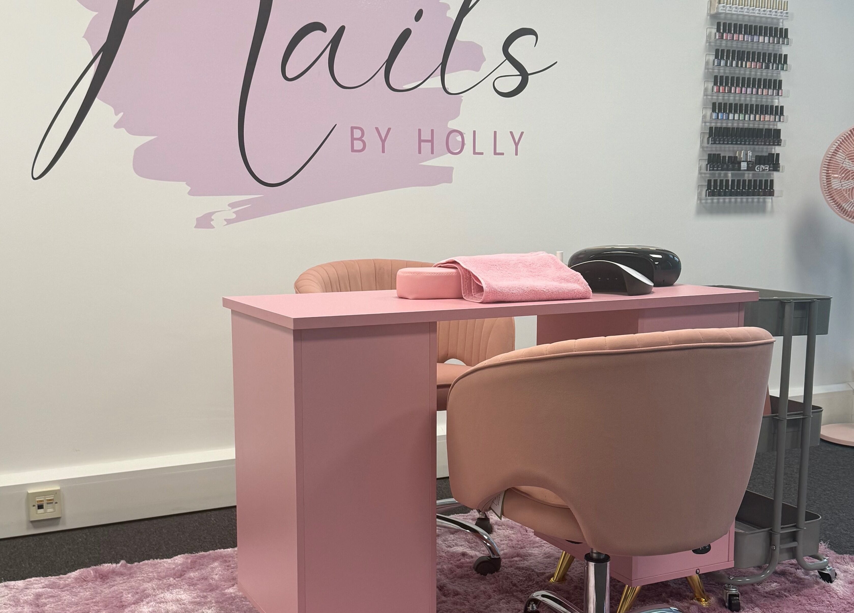 Stylish nail salon setup at Nails By Holly, Great Blakenham, England, featuring pink decor and manicure stations.