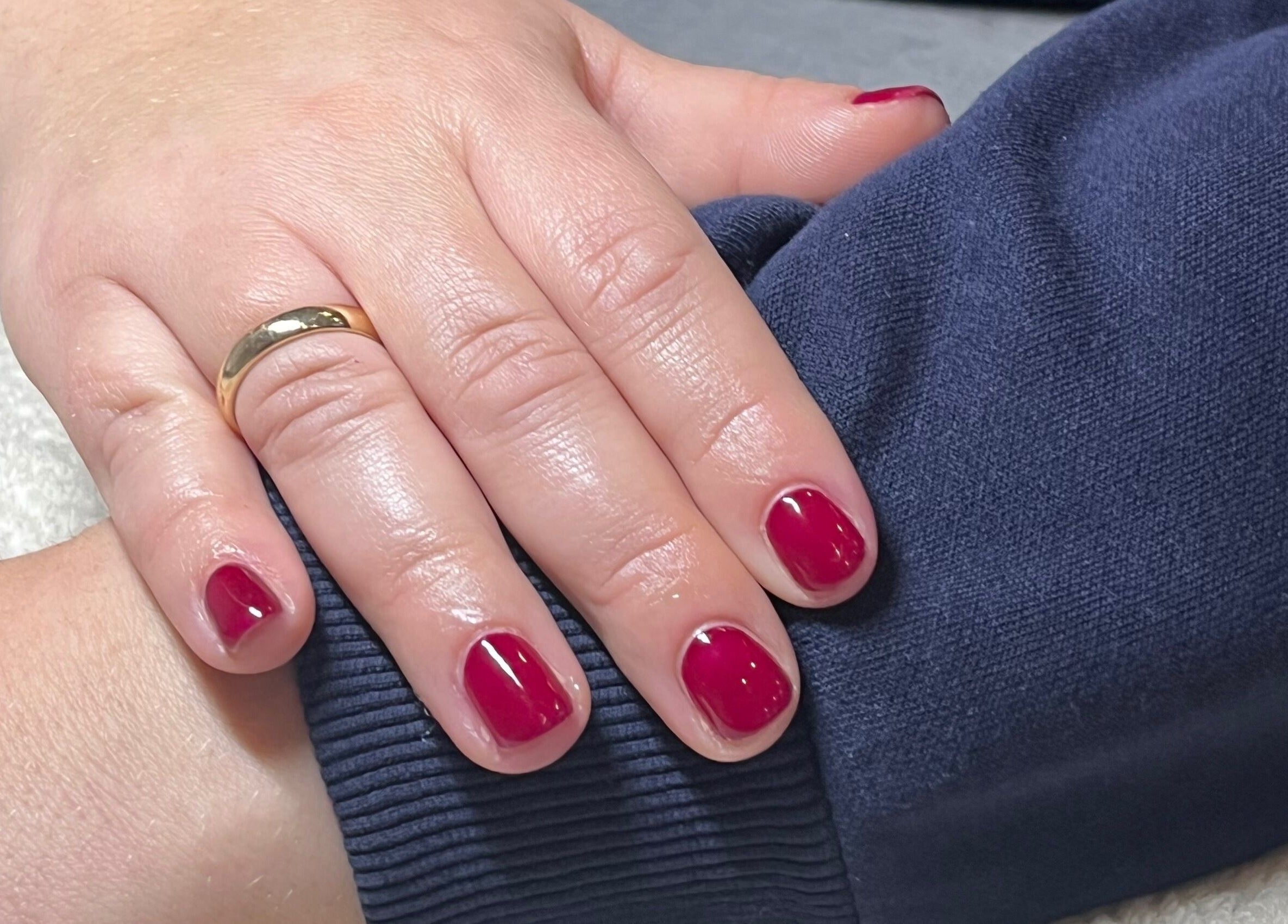 Elegant red nails with a gold ring at Glossed by Ell, Halesowen, England, GB.