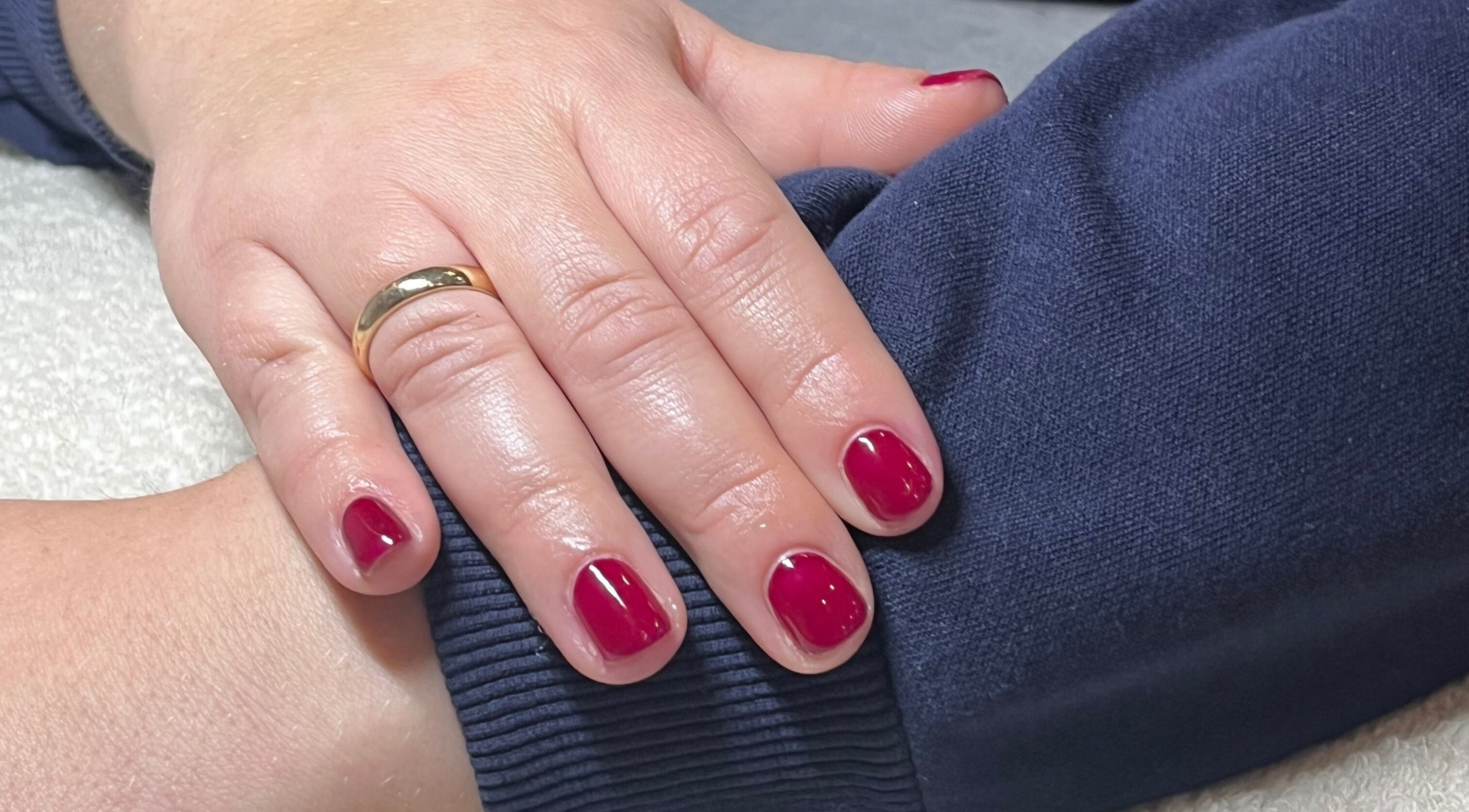 Elegant red nails with a gold ring at Glossed by Ell, Halesowen, England, GB.