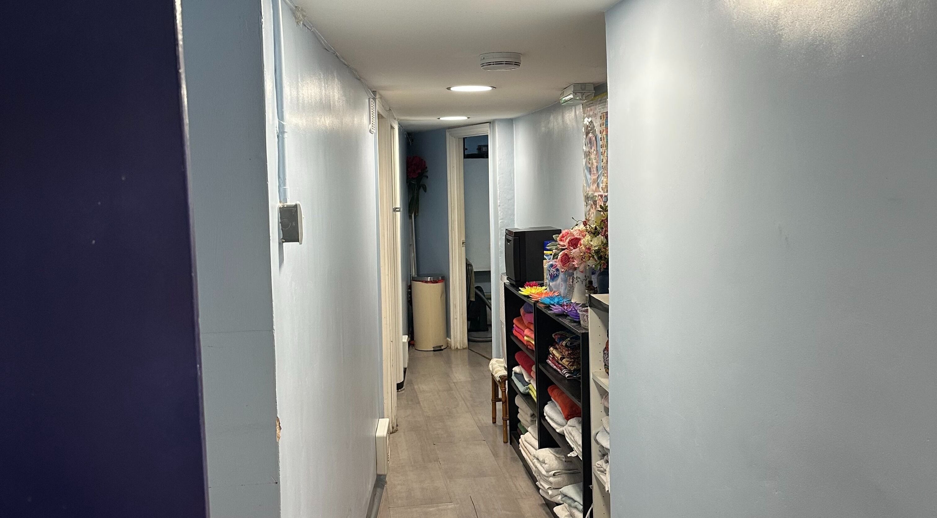 Peaceful hallway at TA Thai Massage, London, England, GB, showcasing tidy shelves and calming decor.