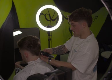 Stylist at Fortuin Studio, Geelong, Victoria AU skillfully cutting client's hair under bright lighting.