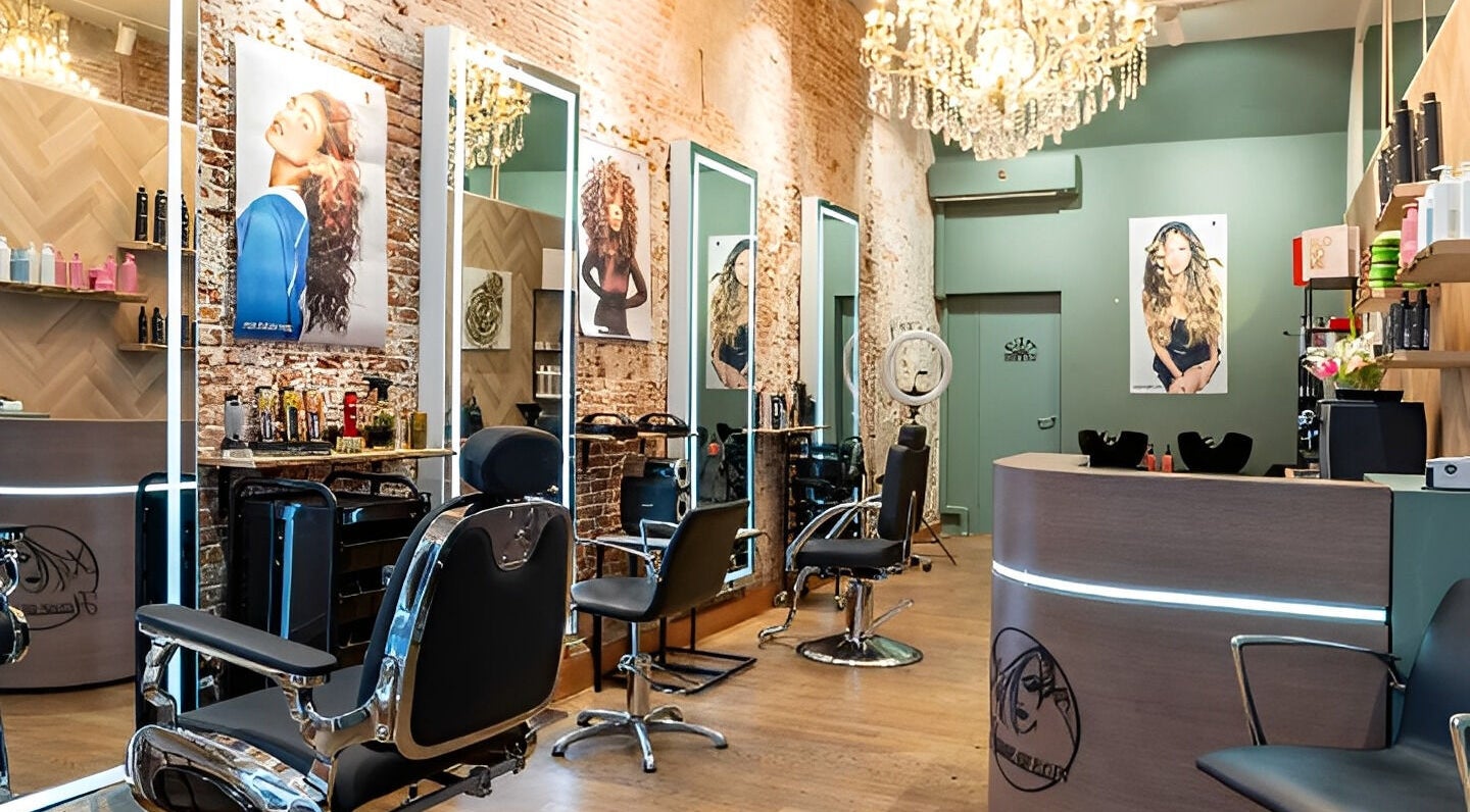 Elegante salon bij HOUSE OF ELIN (BARBER & COIFFEUR) in Amsterdam, Noord-Holland, NL met luxe stoelen en spiegels.