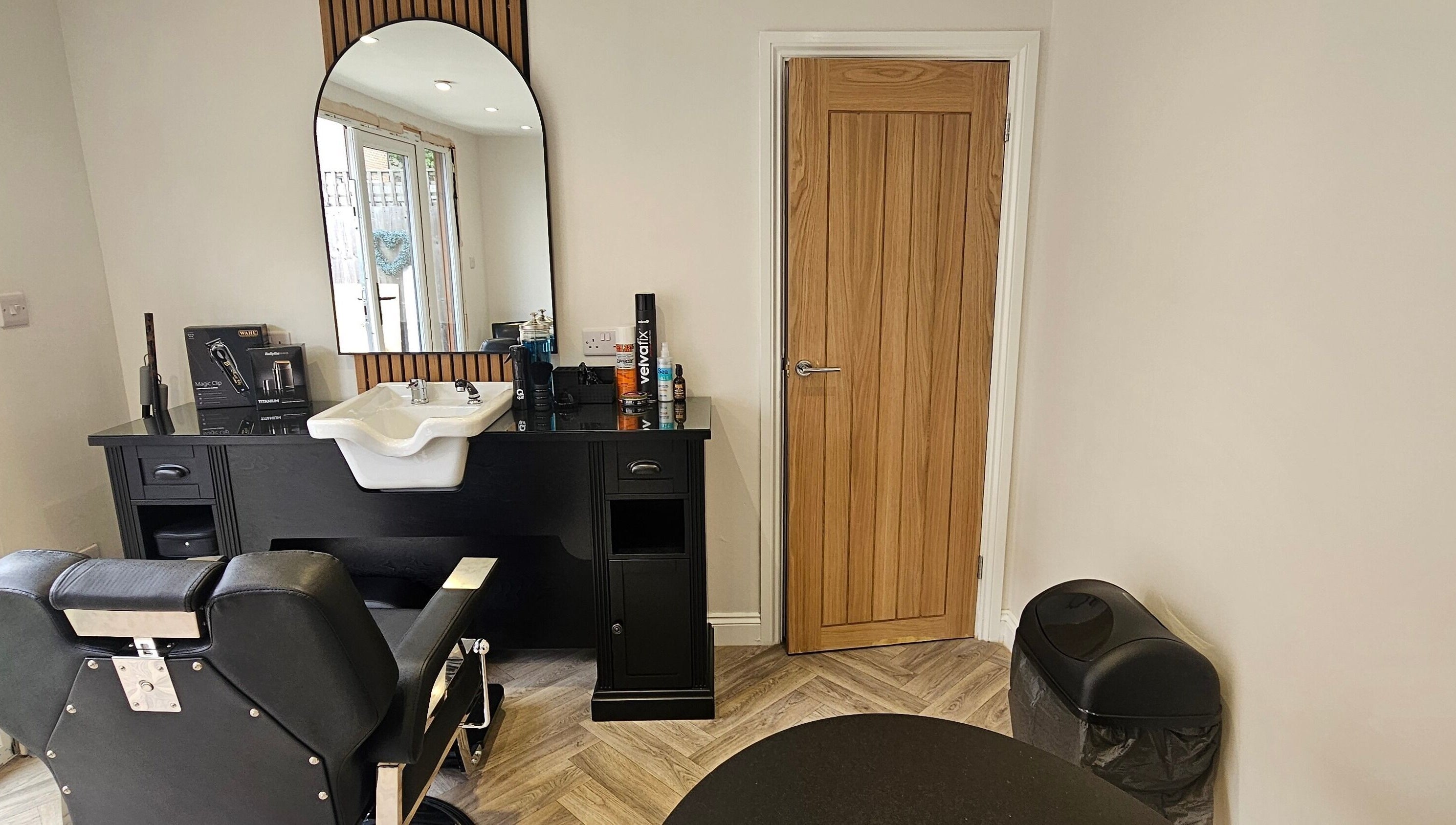 Modern barber station at The Barber Box, Sheffield, England, GB with sleek black chair and wooden accents.