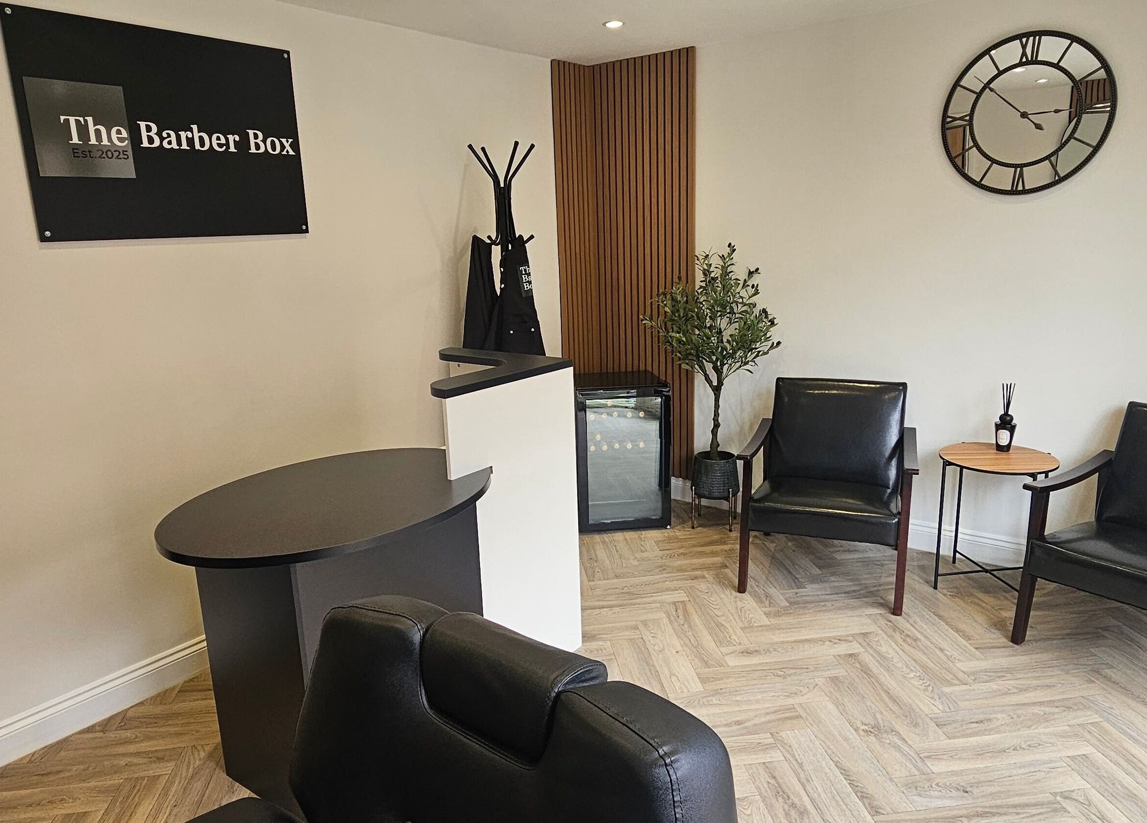 Elegant waiting area at The Barber Box in Sheffield, England, GB, featuring sleek black chairs and a stylish décor.
