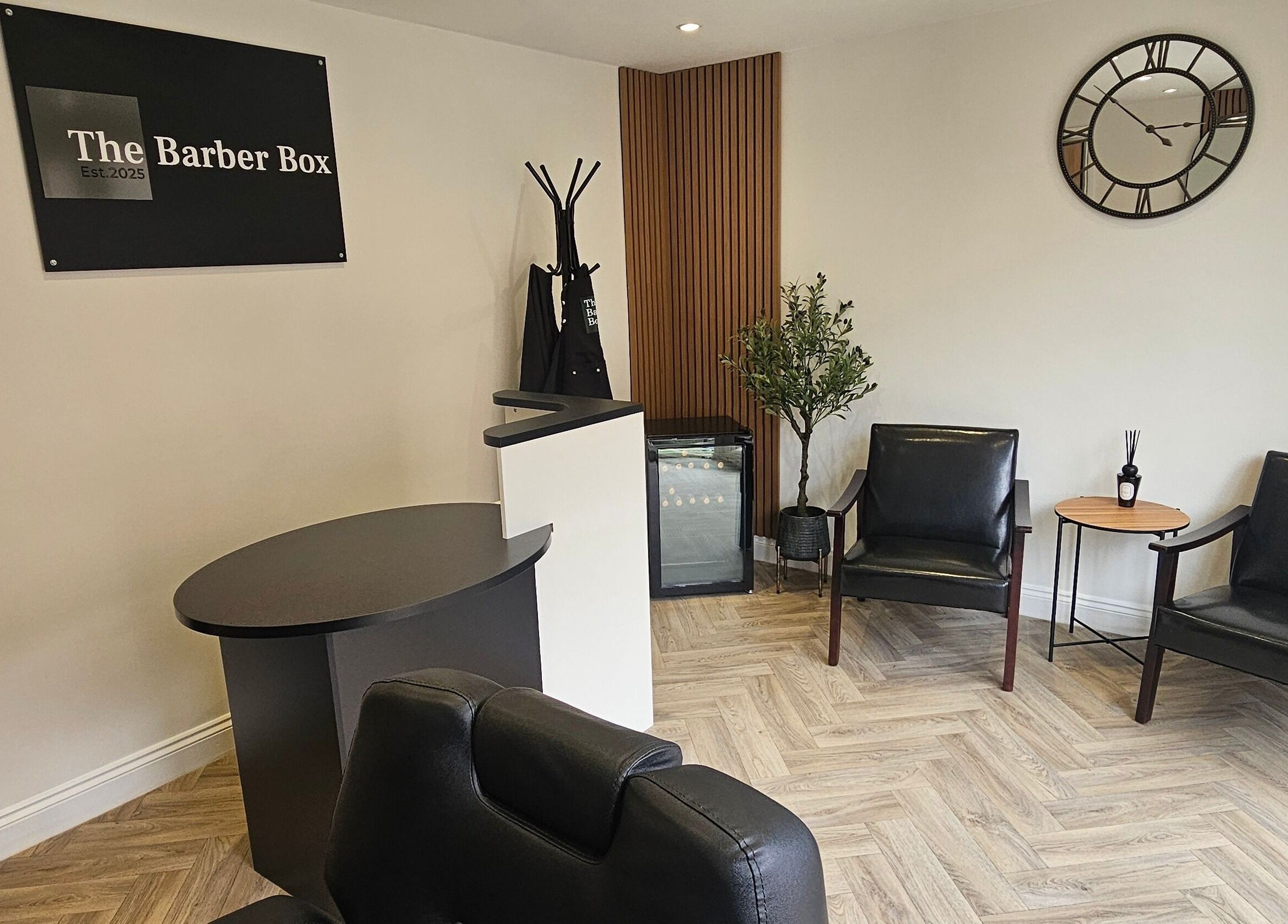 Elegant waiting area at The Barber Box in Sheffield, England, GB, featuring sleek black chairs and a stylish décor.