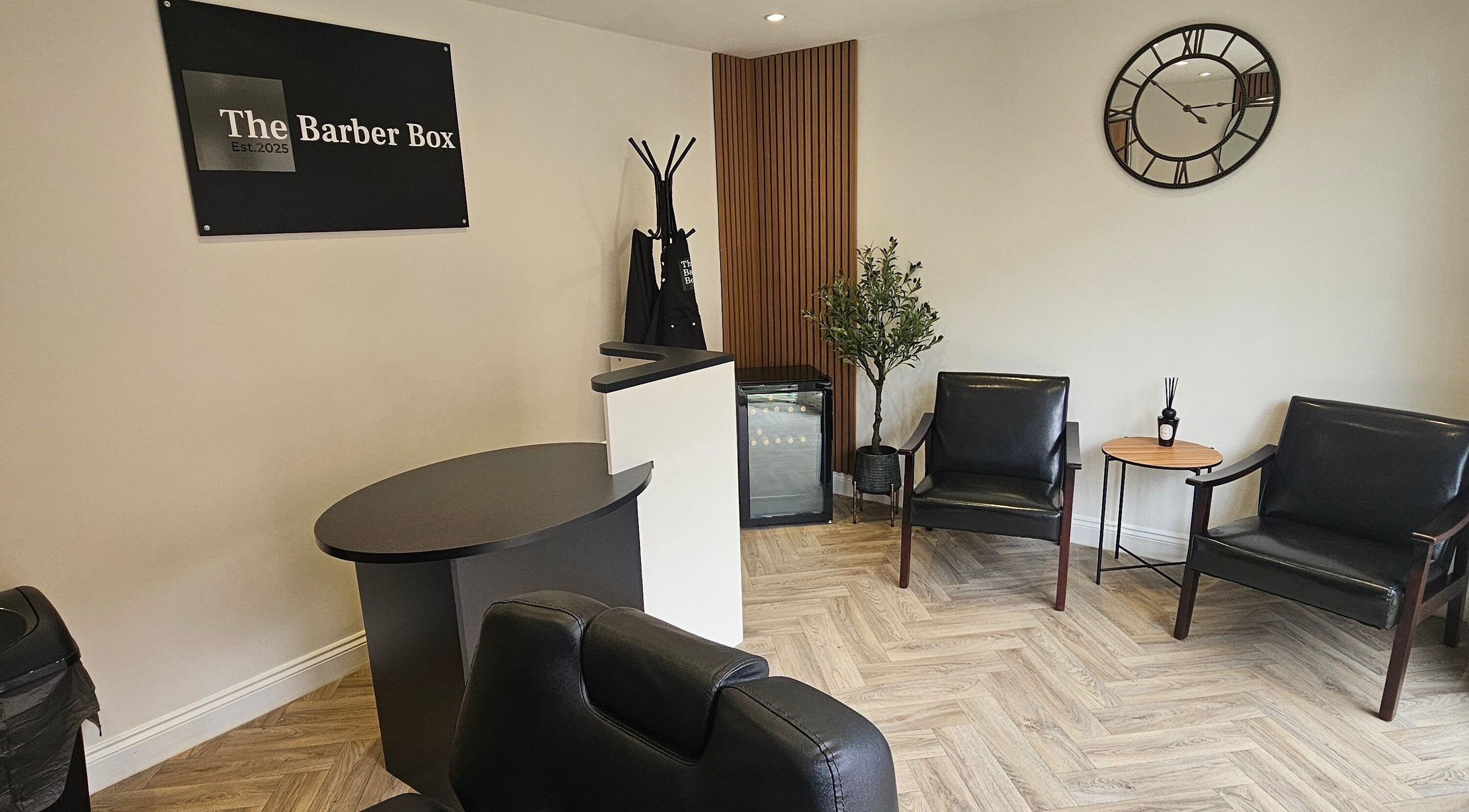 Elegant waiting area at The Barber Box in Sheffield, England, GB, featuring sleek black chairs and a stylish décor.