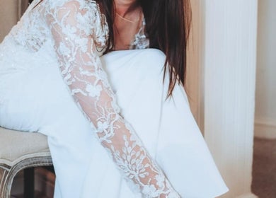 A bride adjusting her shoe in a lace dress at Charlotte Jennifer Makeup & Wellness, Gravesend, England, GB.