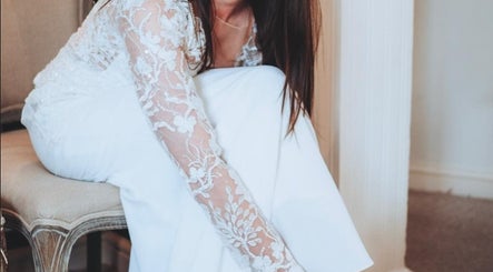 A bride adjusting her shoe in a lace dress at Charlotte Jennifer Makeup & Wellness, Gravesend, England, GB.