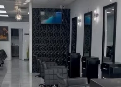Modern salon interior at Jk Braiding Spot in Arlington, Texas. Features sleek black styling chairs and mirrors.