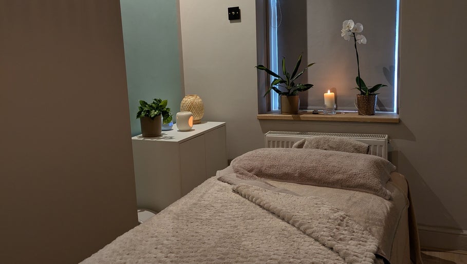 Tranquil relaxation room at Azure Wellness, Combe Martin, England, GB, featuring a cozy massage bed and candles.